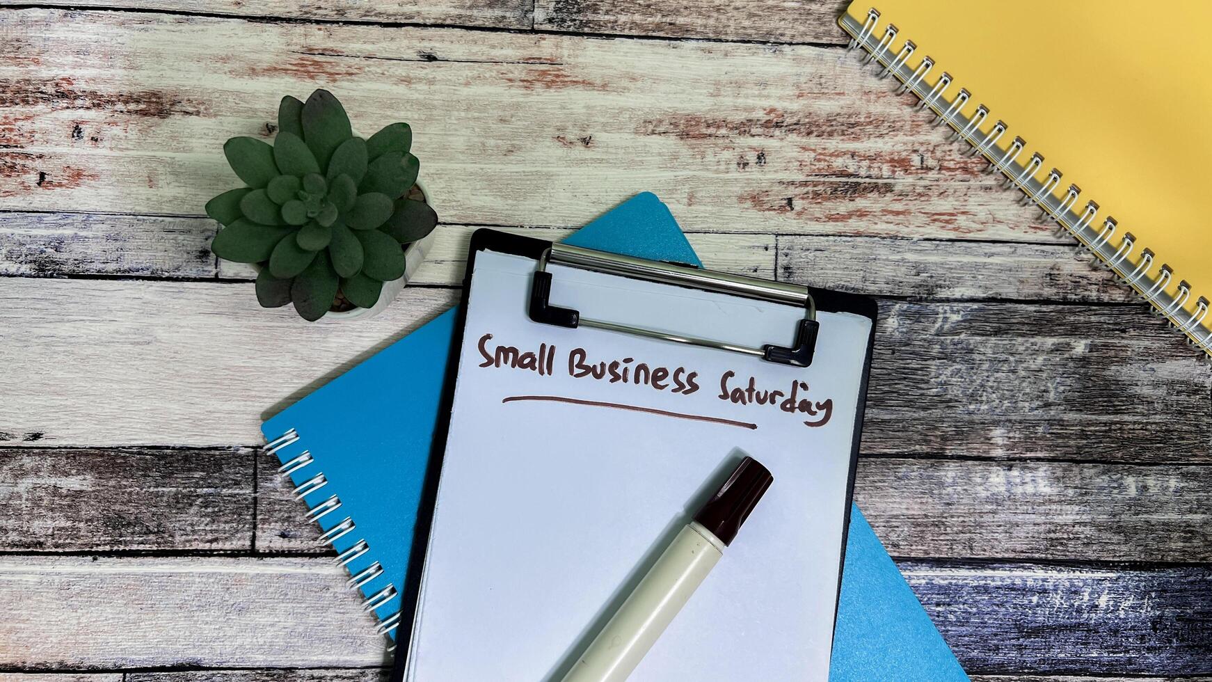 Concept of Small Business Saturday write on paperwork isolated on wooden background. photo