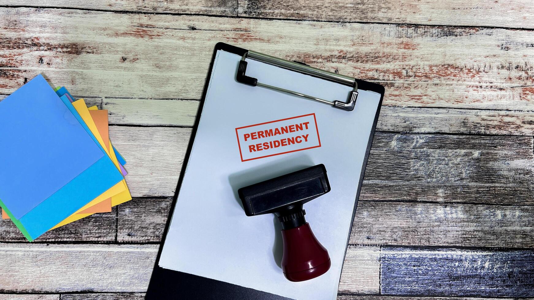 Red Handle Rubber Stamper and Permanent Residency text on a paperwork isolated on wooden background photo