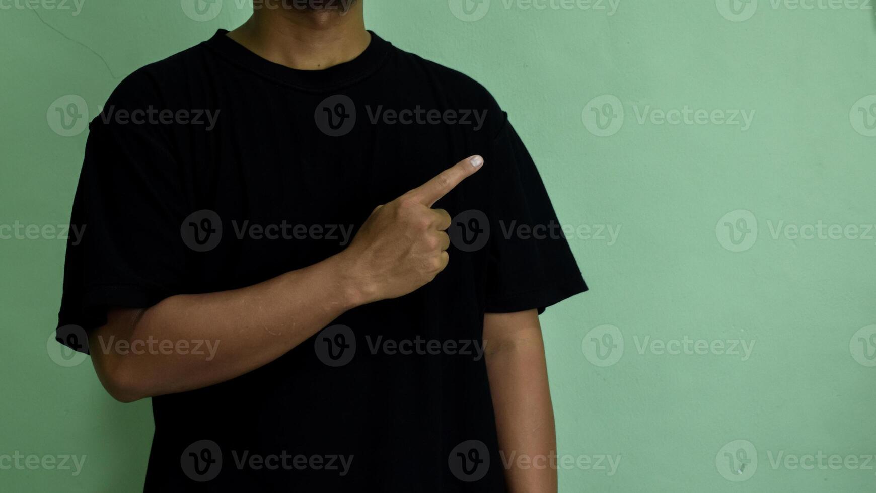Young man looks and points finger to side at mock-up space for you presentation photo