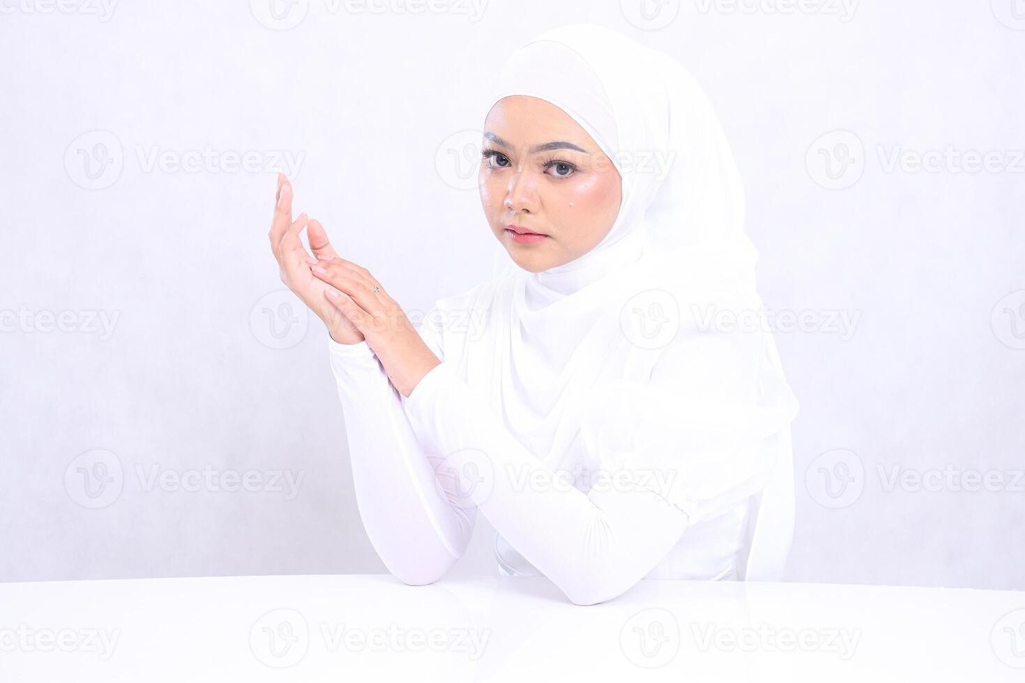 the charm of a veiled woman to the camera with perfect and healthy radiant white skin, both hands attached to the right side isolated on a white background. closeup face with makeup for skincare photo