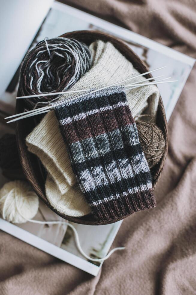 Hand knitted socks with needles and yarn ball in a basket. Concept for handmade and hygge slow life. photo