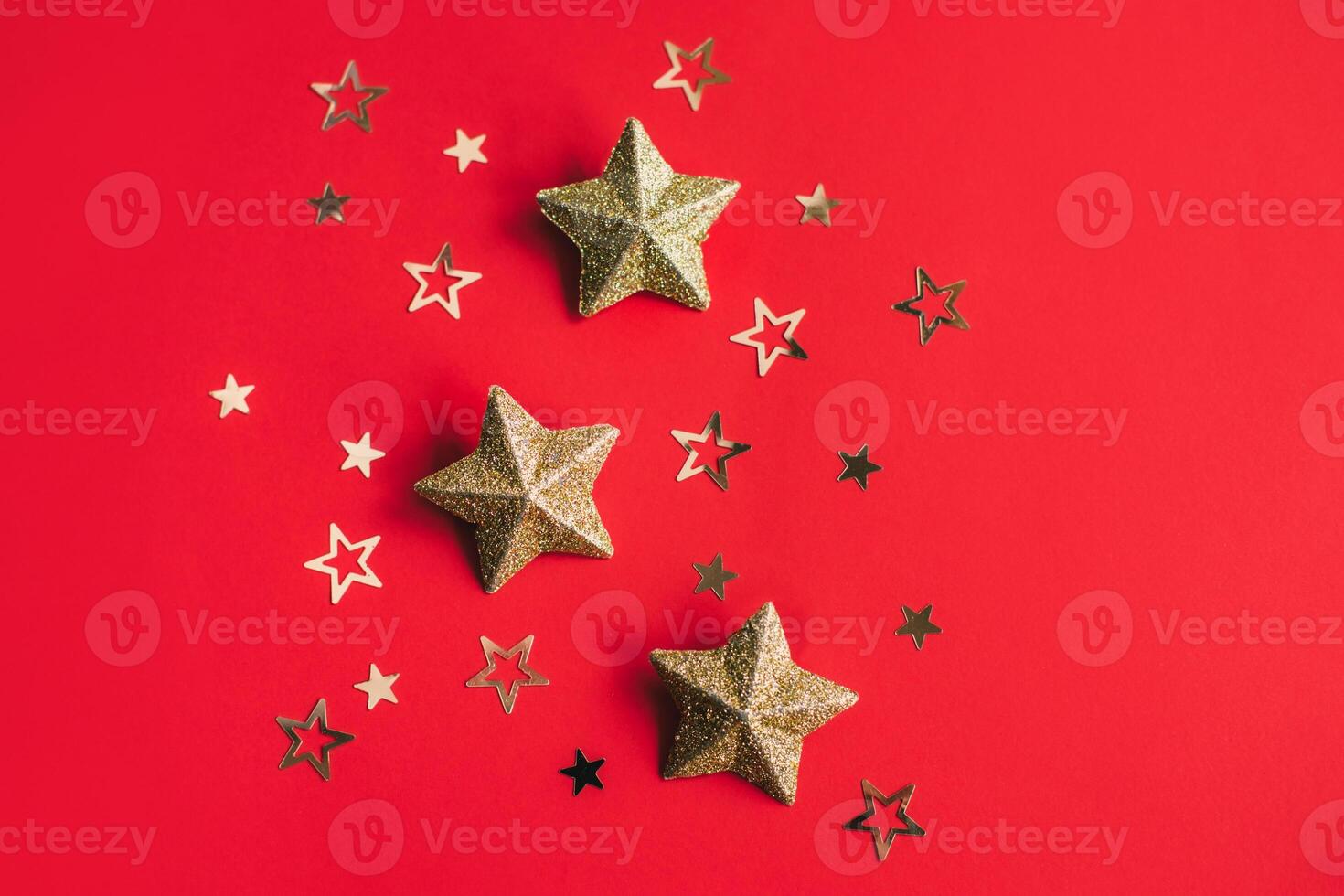 Golden sparkling stars on a red background. Flat lay. photo