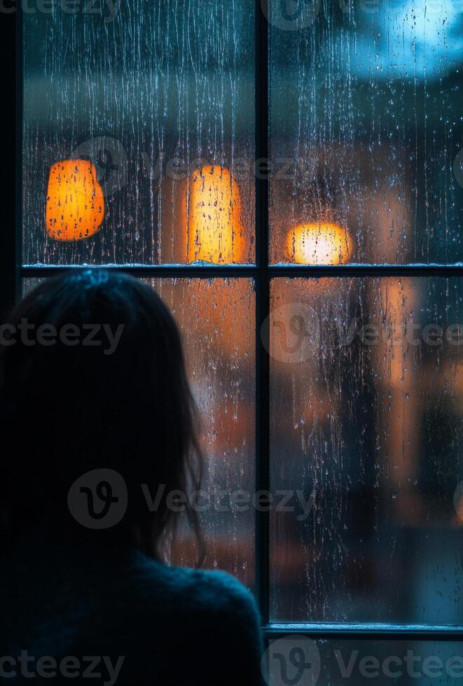 A person staring out of a rain-soaked window, with raindrops running down the glass, lost in contemplation photo