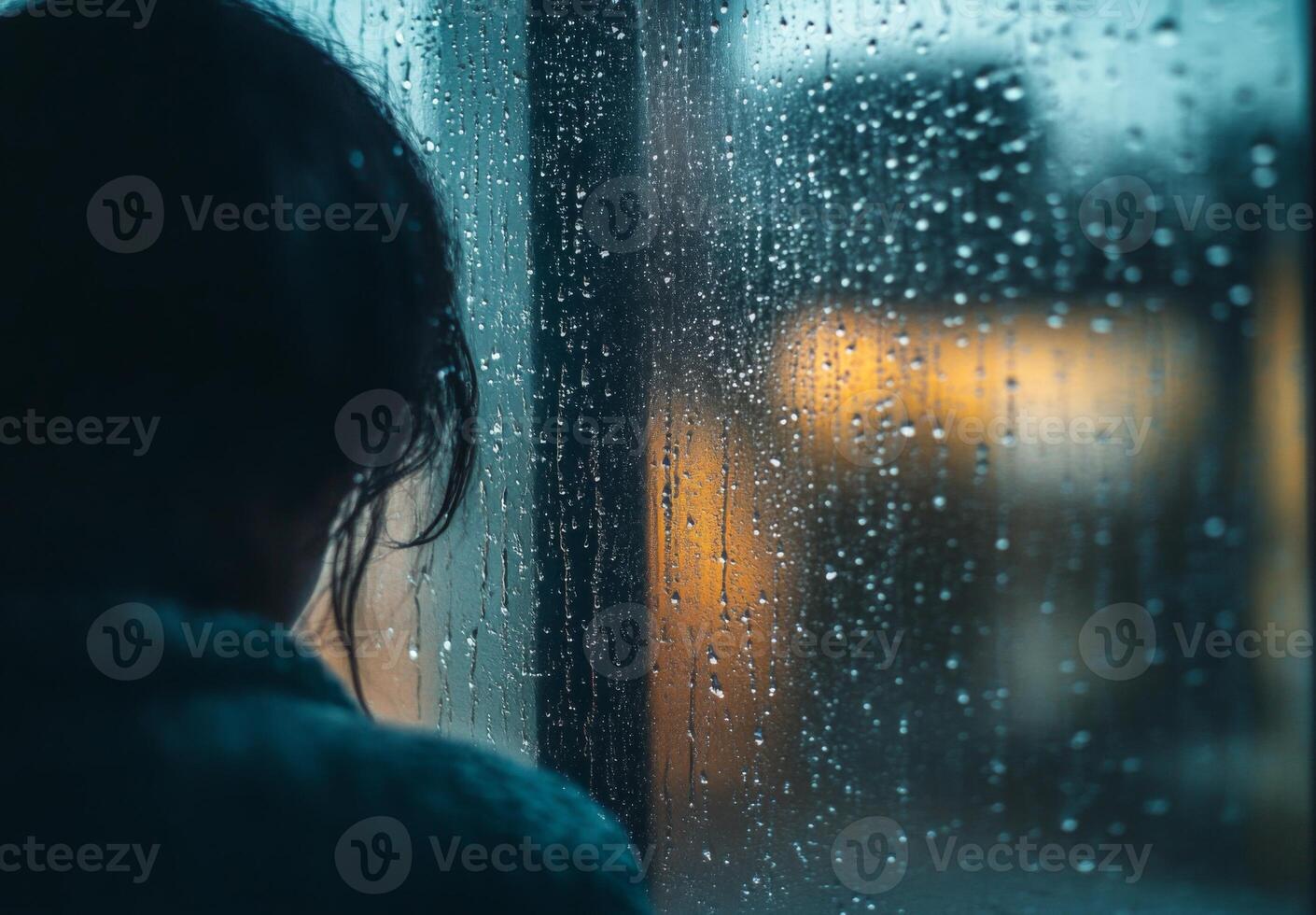 A person staring out of a rain-soaked window, with raindrops running down the glass, lost in contemplation photo