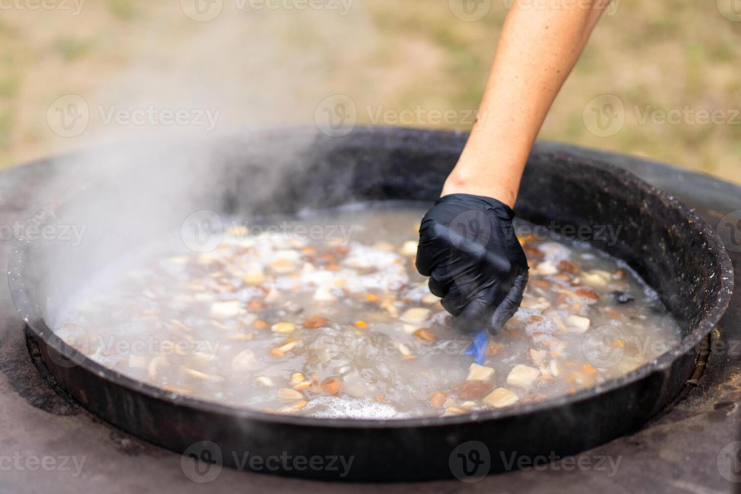 A person stirs a boiling pot of mushroom soup photo