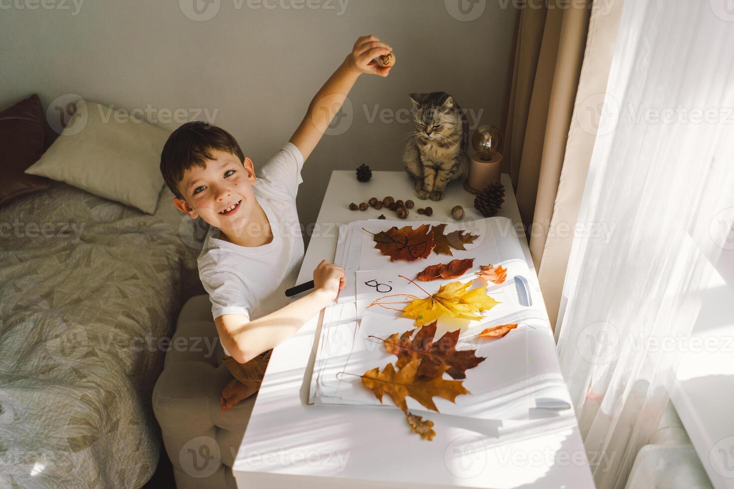 Boy Engaged in Creative Leaf Art Activity at Home with cat photo