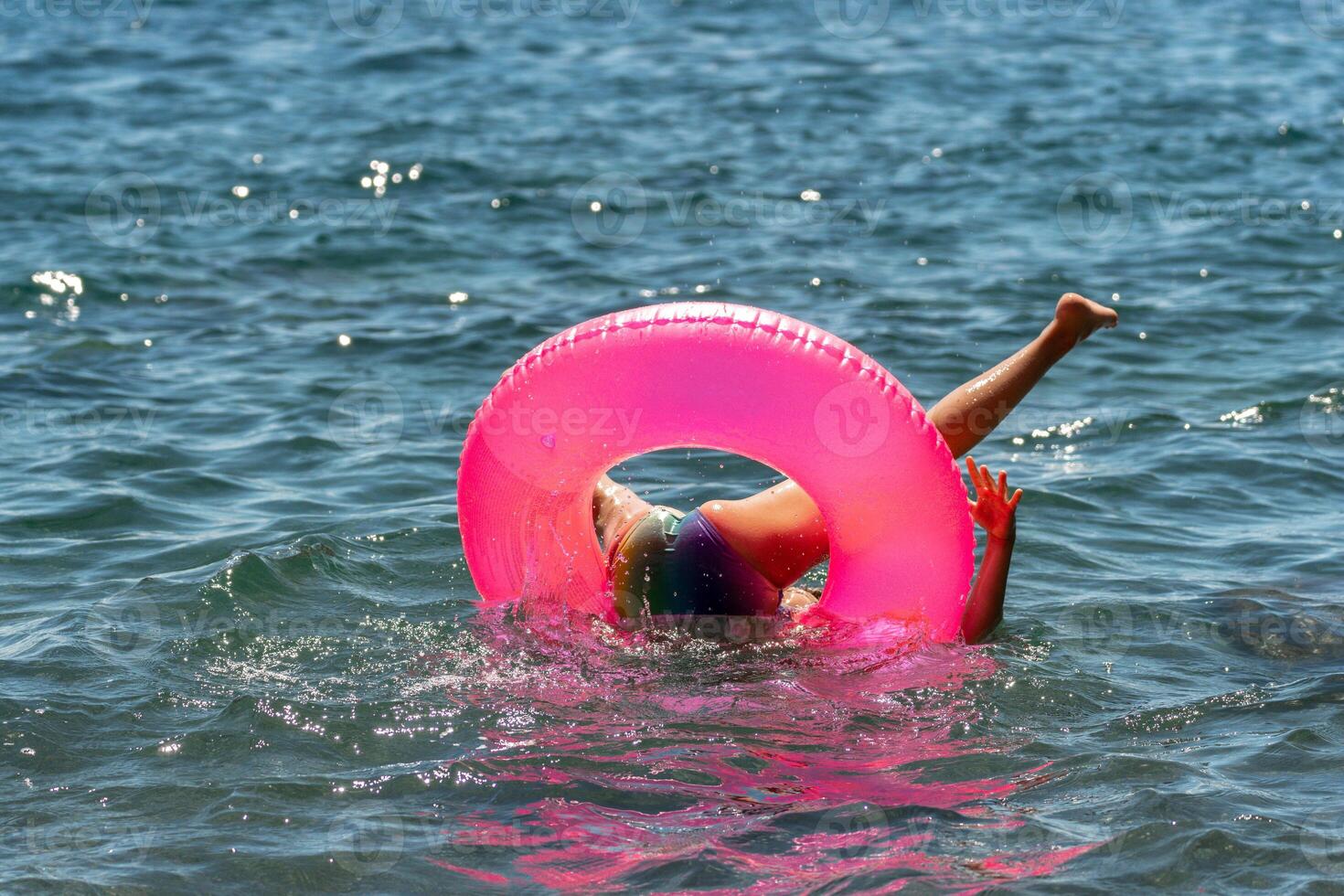 Child Pink Inflatable Ring Ocean Water - A child falls out of a pink inflatable ring into the ocean water. photo