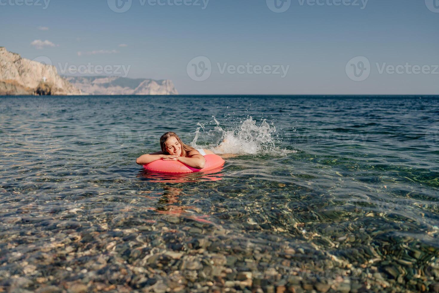 A woman is floating on a pink inflatable raft in the ocean photo