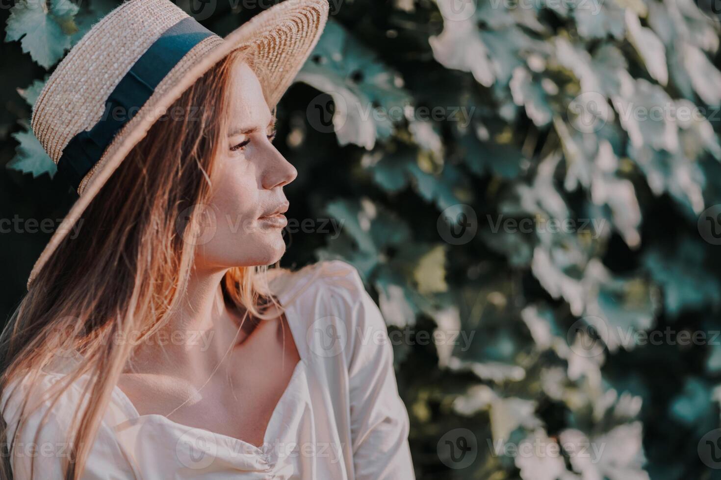 Woman with straw hat stands in front of vineyard. She is wearing a light dress and posing for a photo. Travel concept to different countries photo