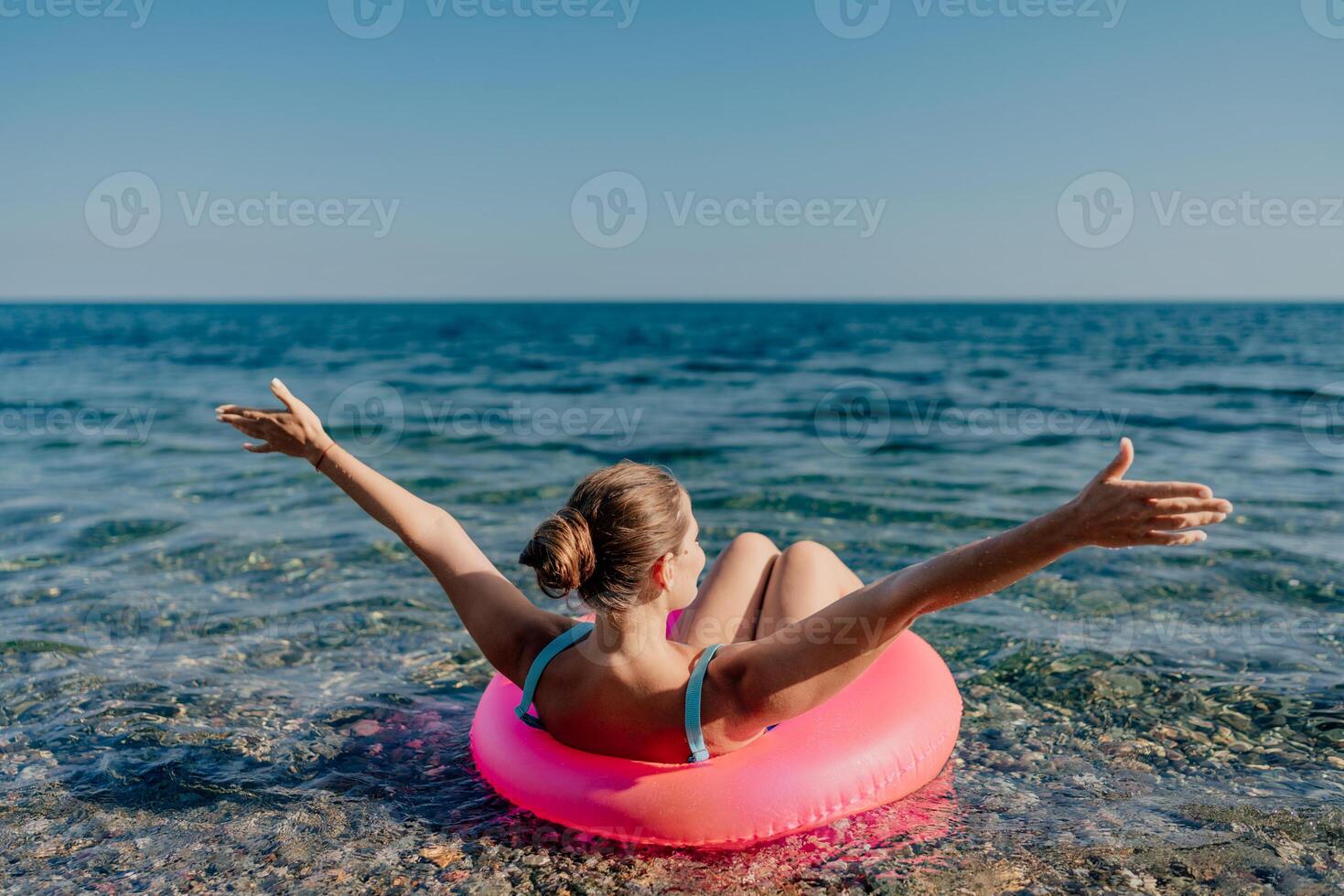 A woman is floating on a pink inflatable raft in the ocean photo