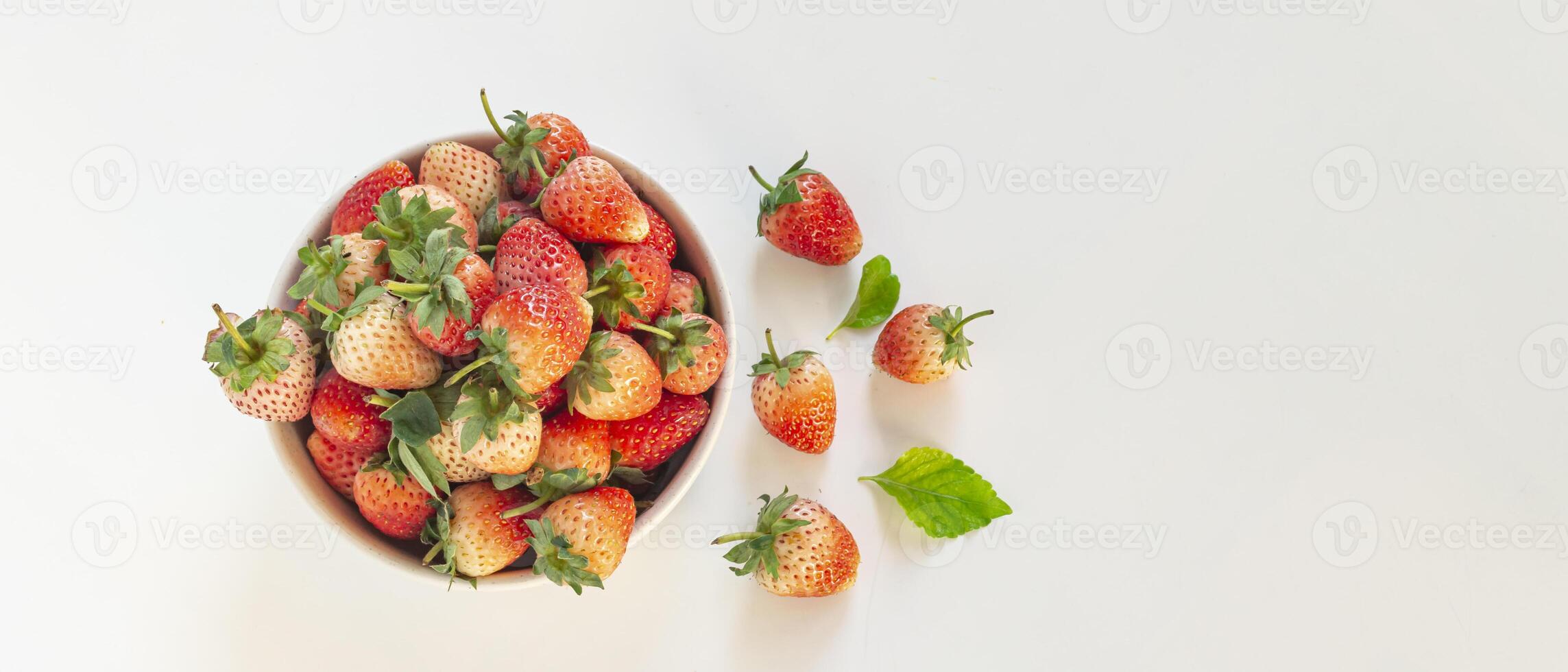 a bowl of strawberries on a white surface photo