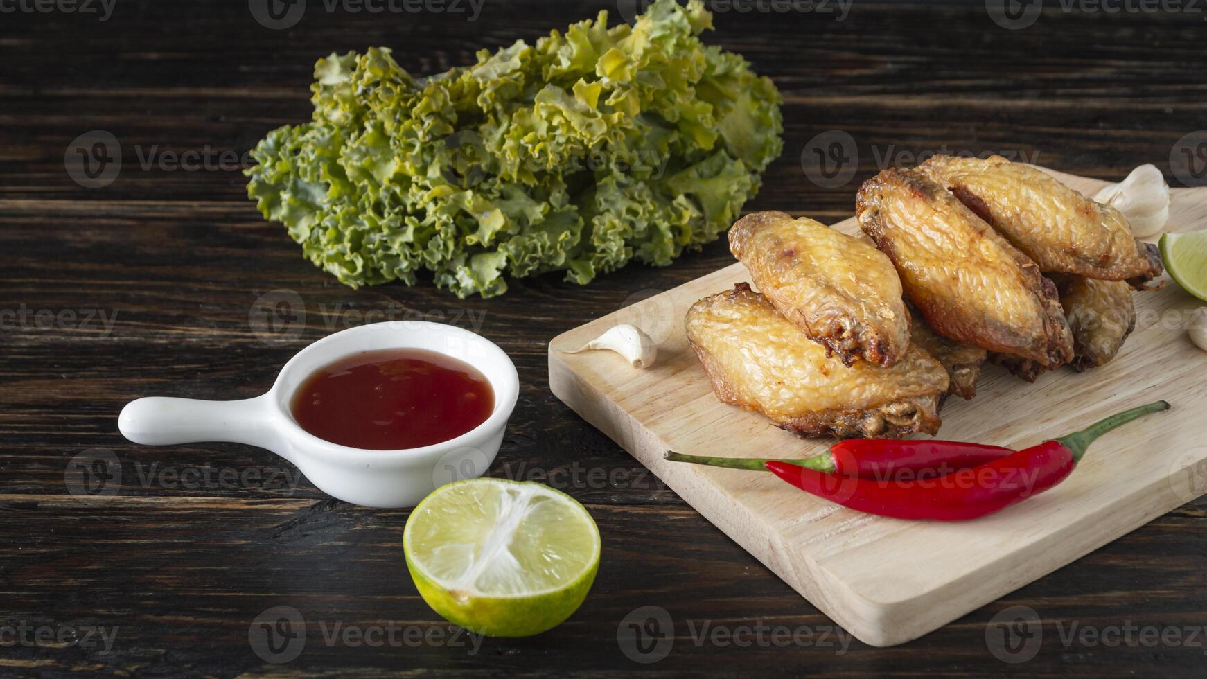 chicken wings with sauce and lettuce on a cutting board photo