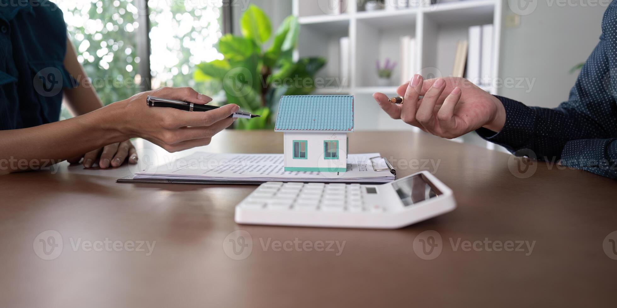 Discussing property details over a contract and house model photo