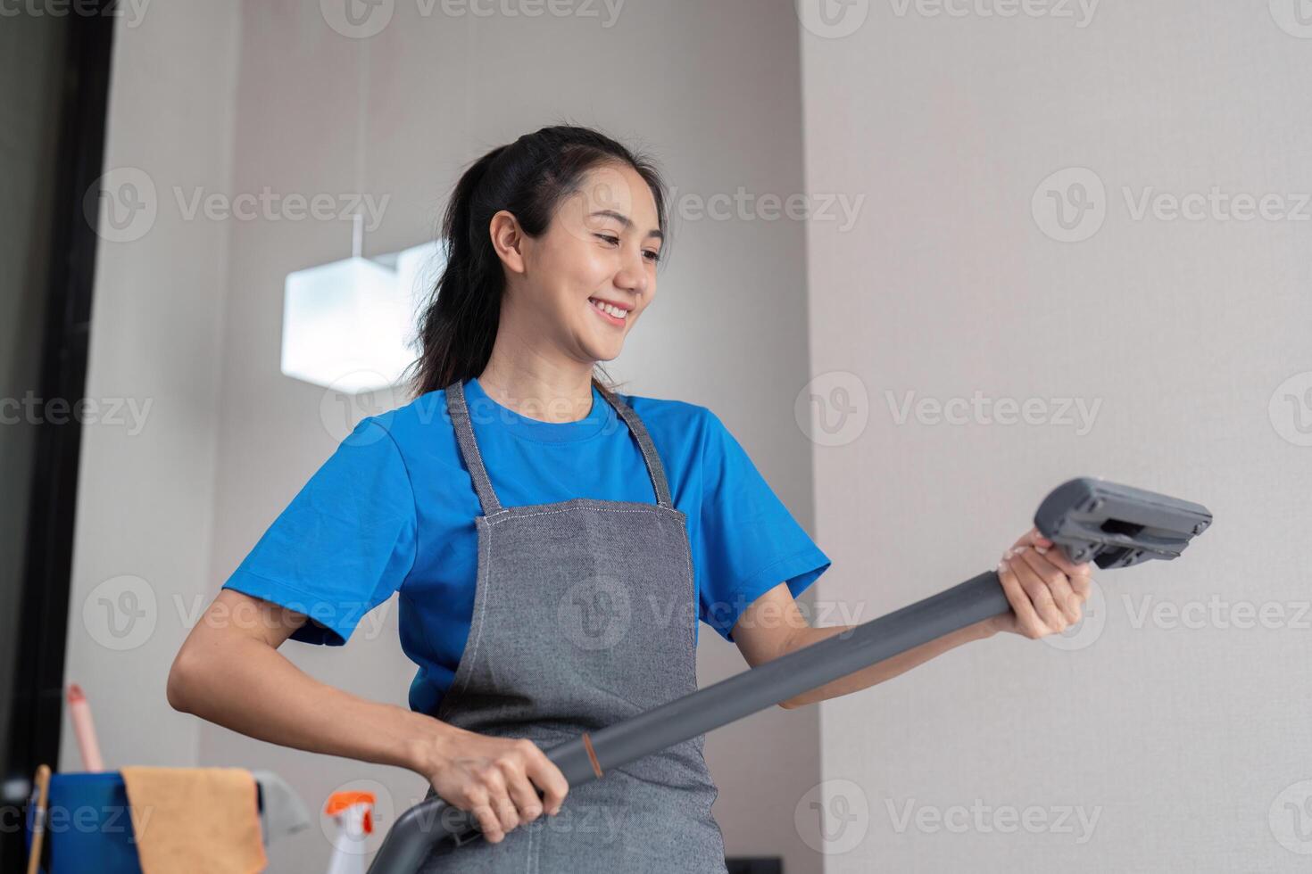 Smiling housekeeper preparing vacuum for cleaning tasks photo