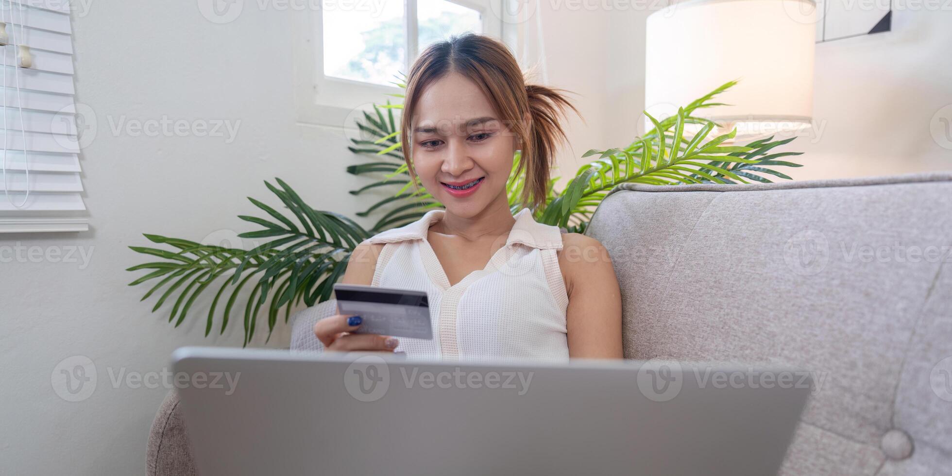 Focused Asian woman exploring online shopping options with credit card, notion of electronic commerce photo