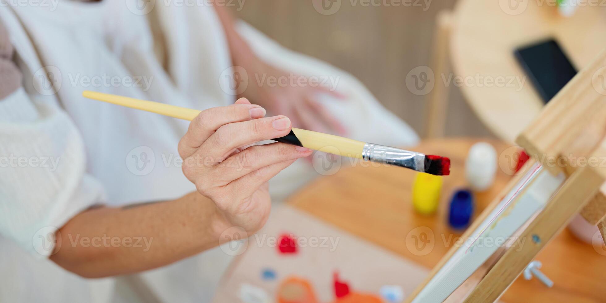 Close up of senior hand holding paintbrush over colorful palette photo