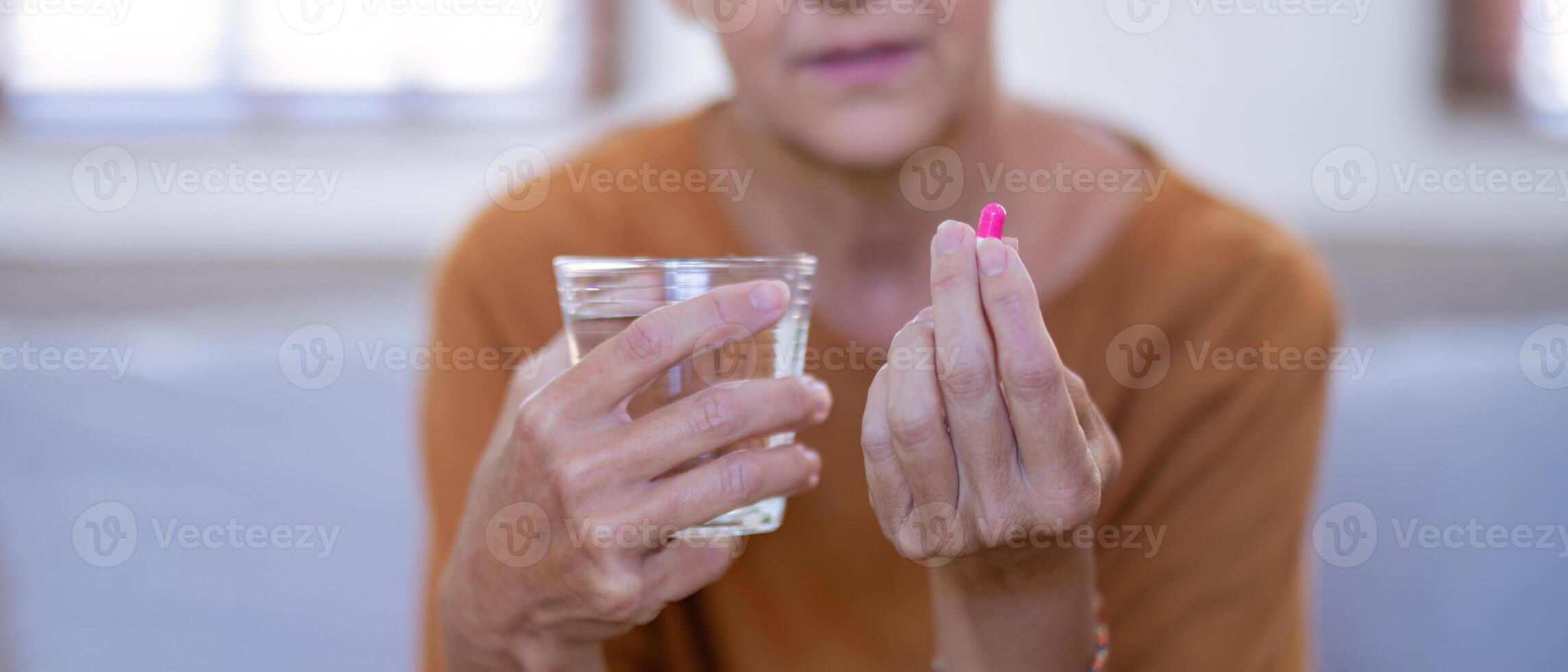 Elderly Woman Holding Pill and Glass of Water for Medication photo