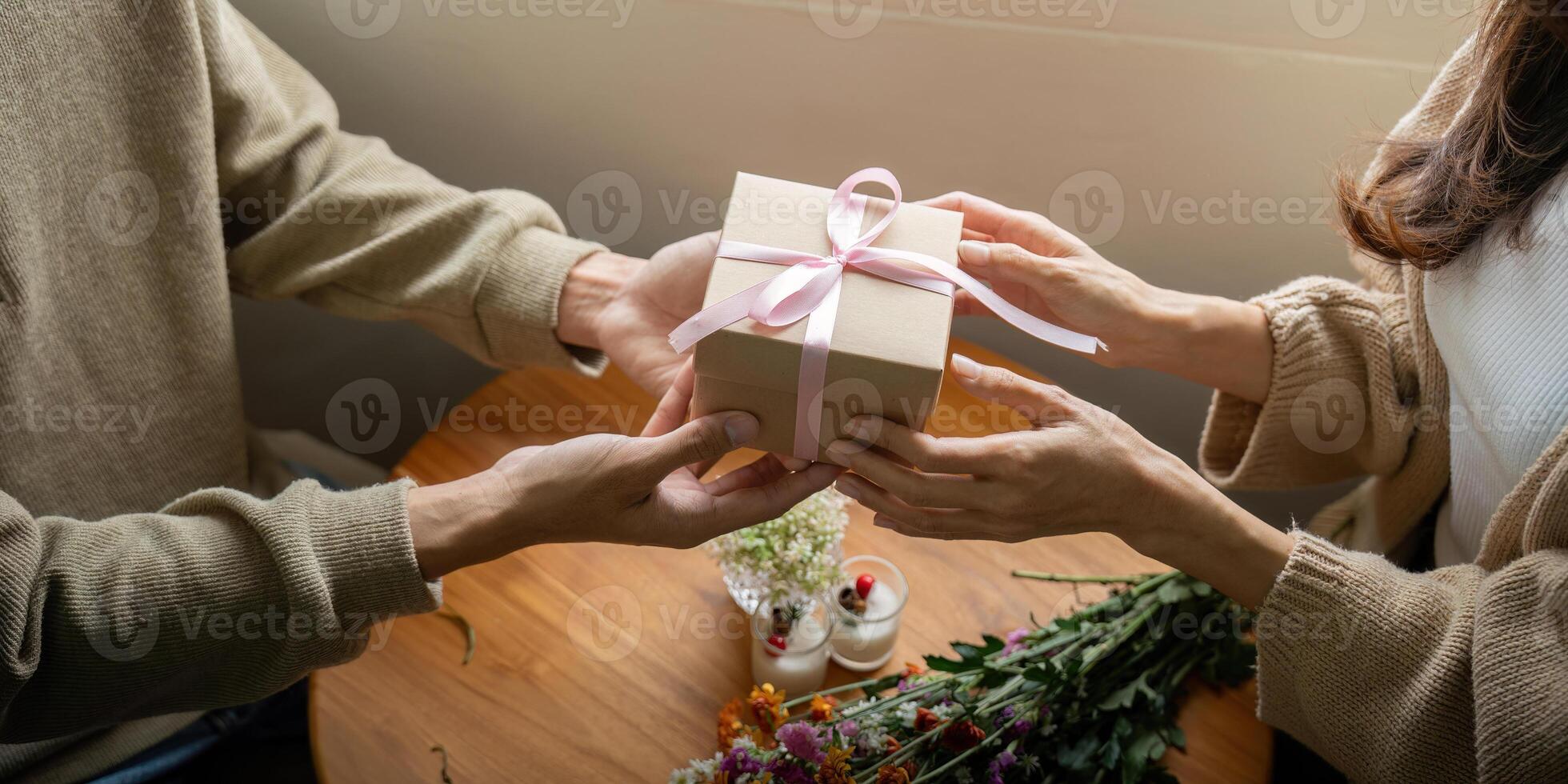 Hands Exchanging a Gift Wrapped with Pink Ribbon photo