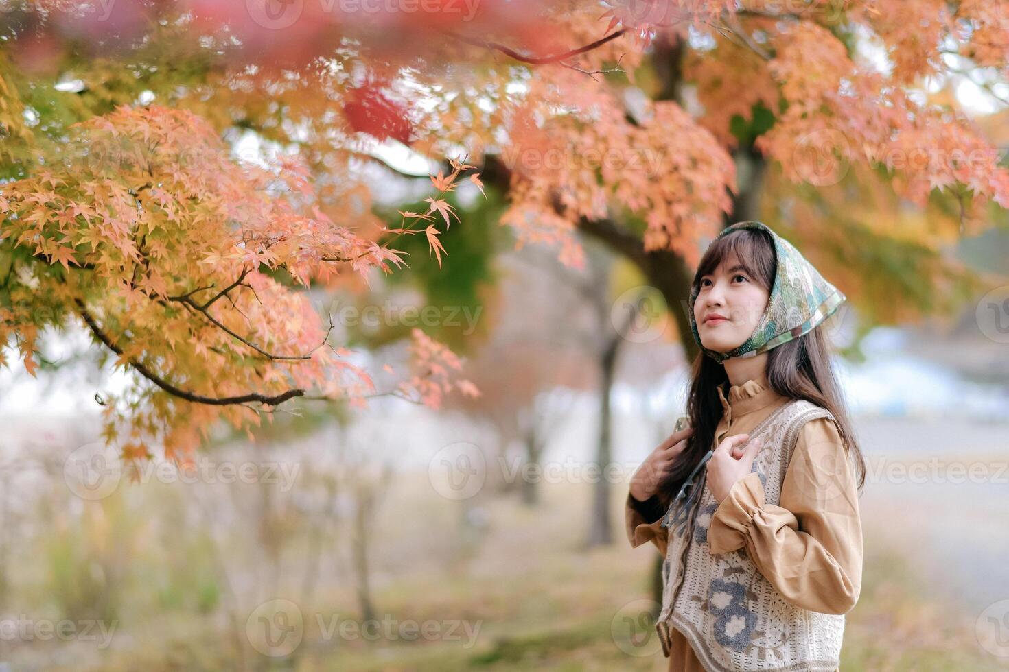 Asian woman in casual dress enjoys Japan's beauty, walking amid vibrant foliage. A cheerful holiday portrait capturing the essence of nature, fashion, and a journey. photo