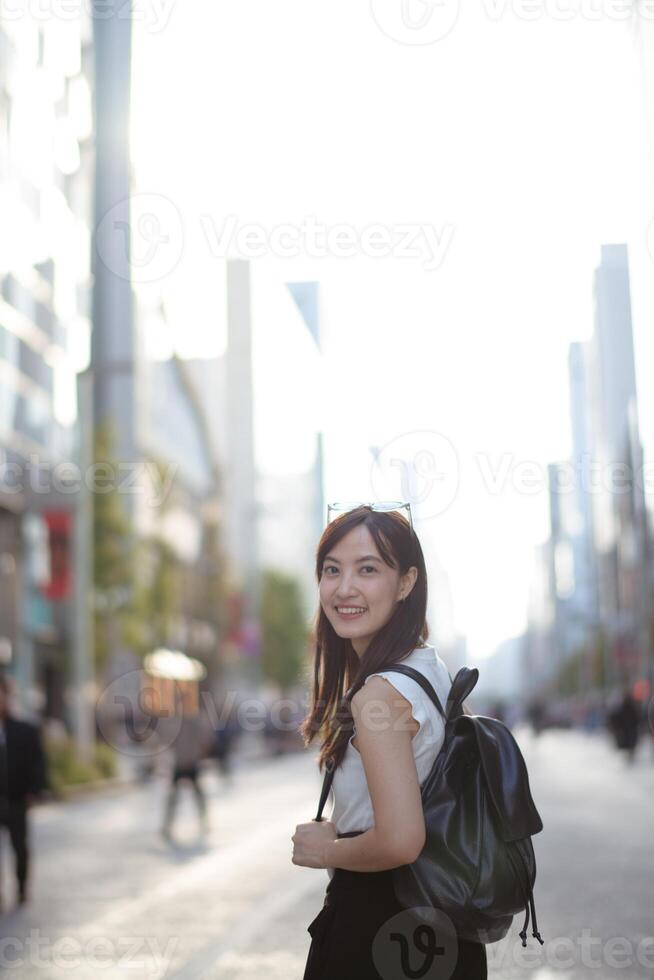 A snapshot of joy in the city, a young Asian woman's smile mirrors the carefree and confident spirit of contemporary living. photo