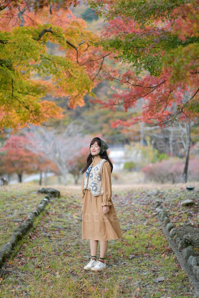 Asian woman in Japan's fall beauty, a cheerful holiday portrait in yellow and red foliage. A journey capturing the essence of nature, fashion, and casual elegance. photo