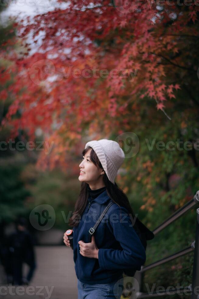 Asian woman in Japan's fall beauty, a cheerful holiday portrait in Kyoto. Vibrant foliage, friends, and smiles by the lake create a joyful and scenic atmosphere. photo