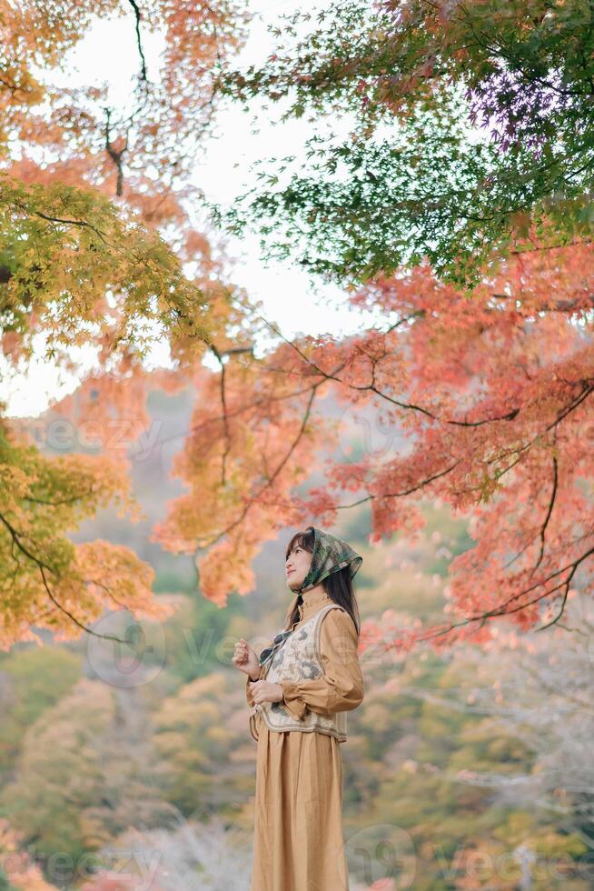 Asian woman in casual dress embraces the fall beauty of Japan, enjoying a holiday filled with smiles, fashion, and vibrant foliage. A cheerful portrait capturing the essence of a vacation. photo