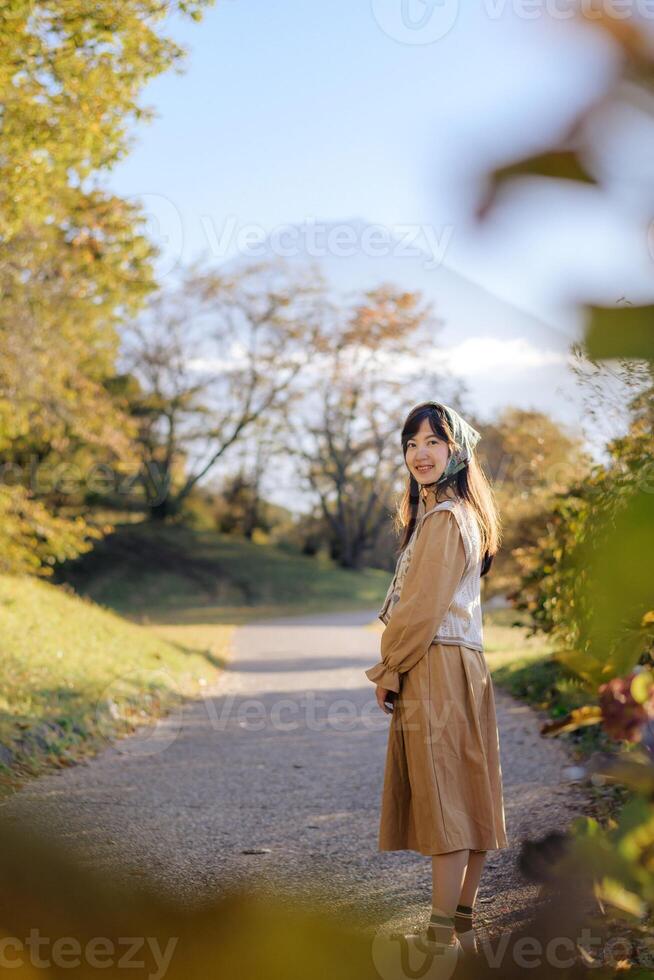 Seasonal delight, Asian woman in a casual dress enjoys fall in Japan. Elegant portrait with colorful maple foliage, capturing her cheerful smile and the beauty of the changing season. photo