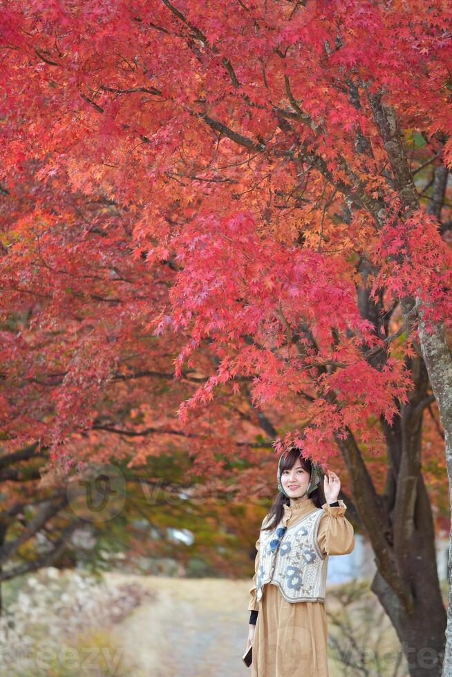 asiático mujer en Japón, rodeado por vibrante otoño follaje, disfruta un fiesta por el lago cerca montar fuji amigos, autofotos, y alegre momentos capturado en un alegre retrato. foto