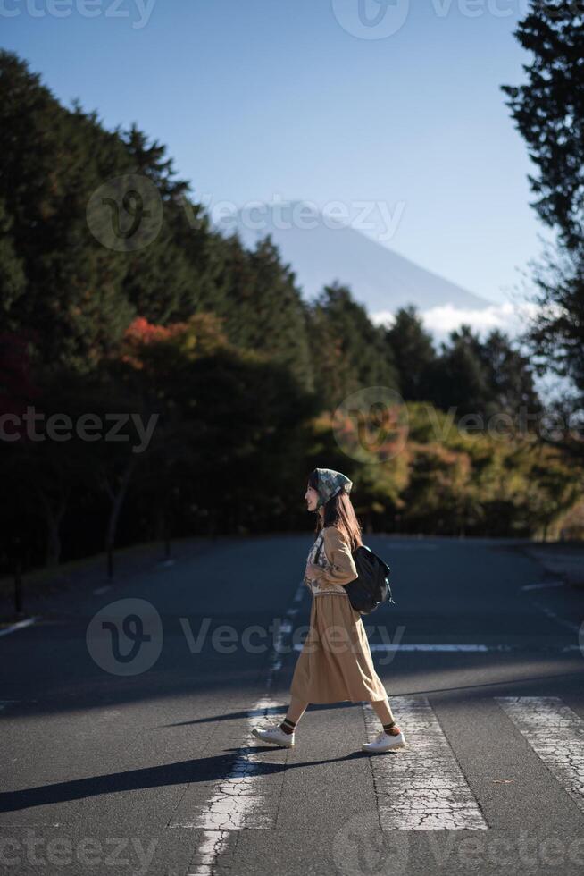 Vibrant vacation vibes, Asian woman in casual dress enjoys Tokyo near Mount Fuji, capturing the energy of the crowd, shopping, and creating a cheerful portrait with Tanuki Lake in the background. photo