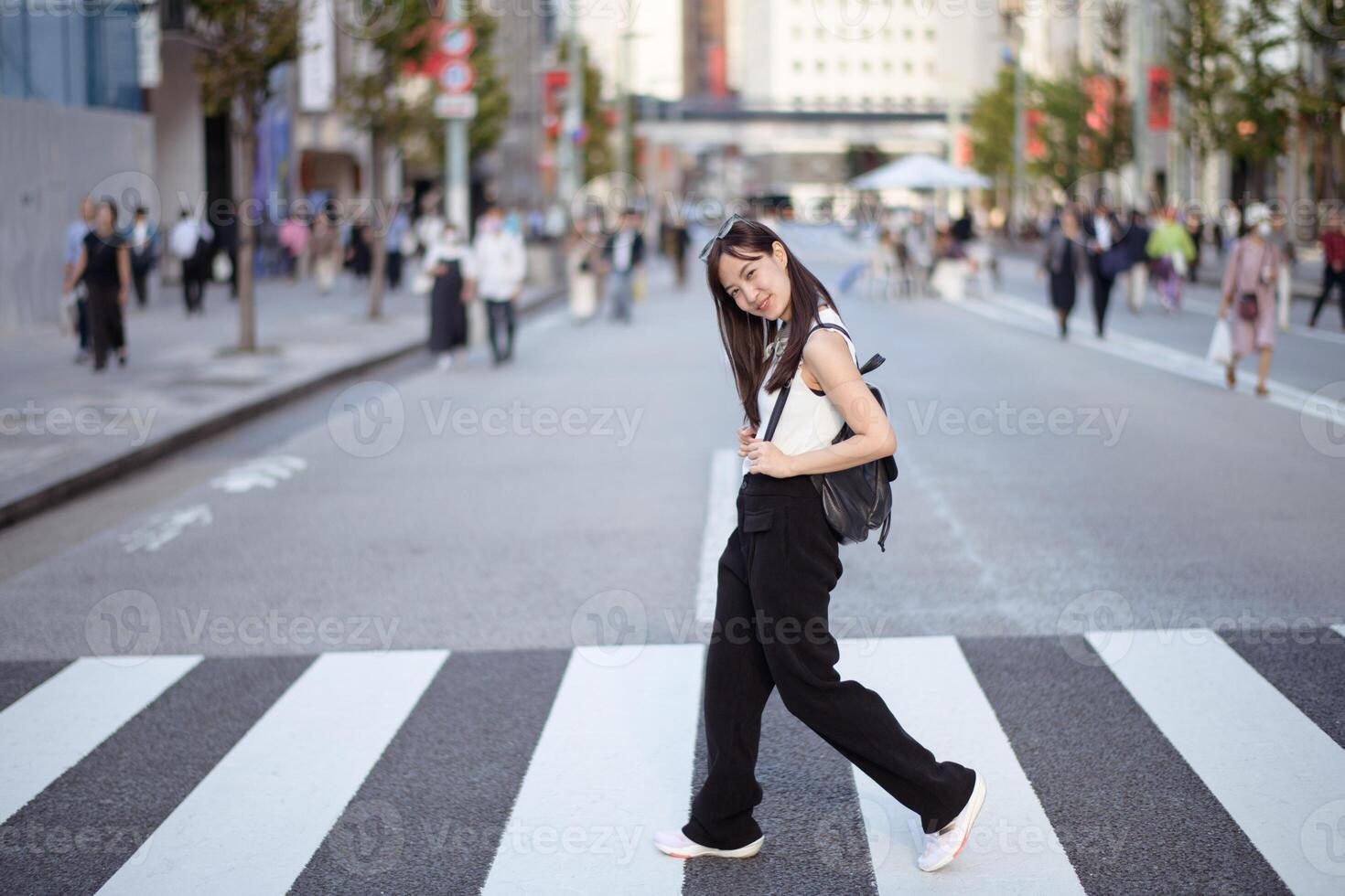 In the heart of the city, fashionable Asian woman stands confidently, embodying the fusion of modern style and the vibrancy of urban living. photo