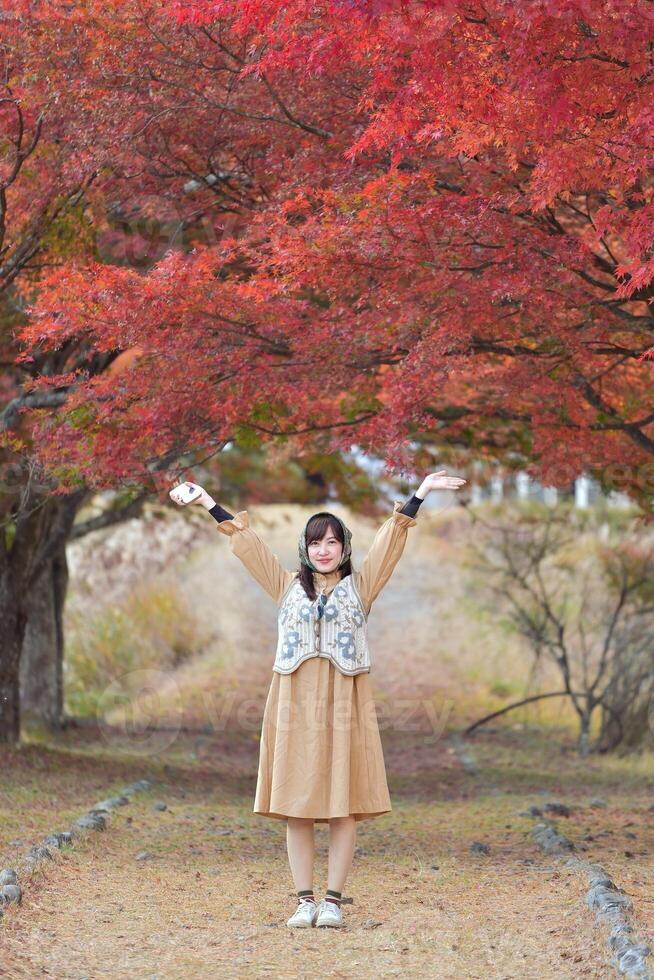 Asian woman in casual dress embraces the beauty of Japan's autumn. A holiday portrait capturing friends, selfies, and joyful moments by the lake near Mount Fuji. photo