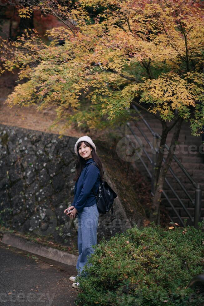 Asian woman in casual dress enjoys Japan's autumn in Kyoto. A cheerful holiday portrait capturing friends, smiles, and colorful foliage by the lake. photo
