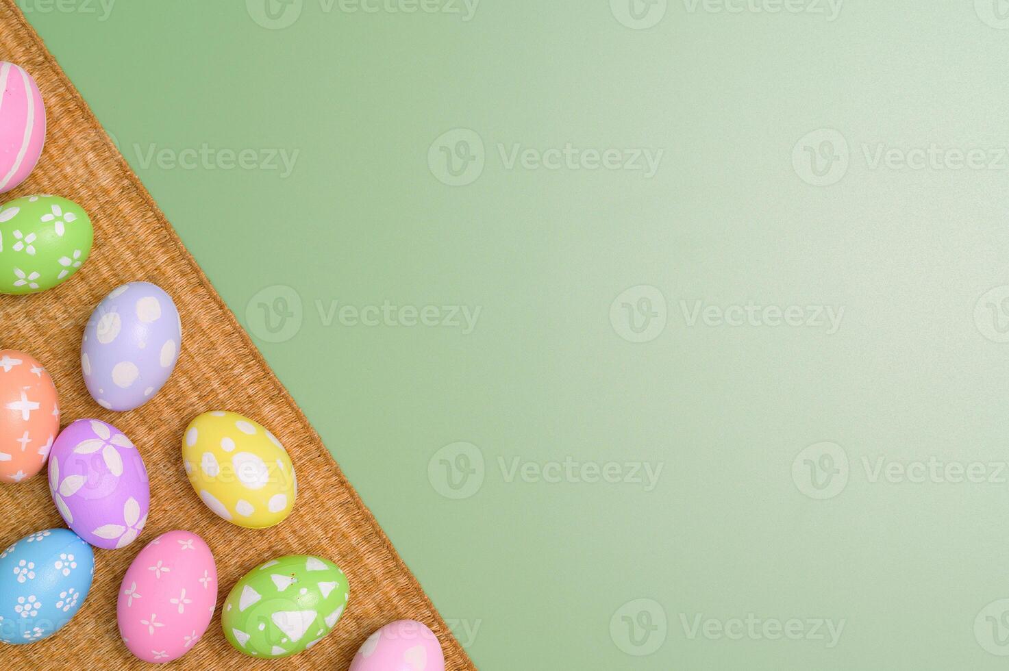 Happy Easter holiday greeting card design concept. Colorful Easter Eggs and spring flowers on pastel green background. Flat lay, top view, copy space. photo