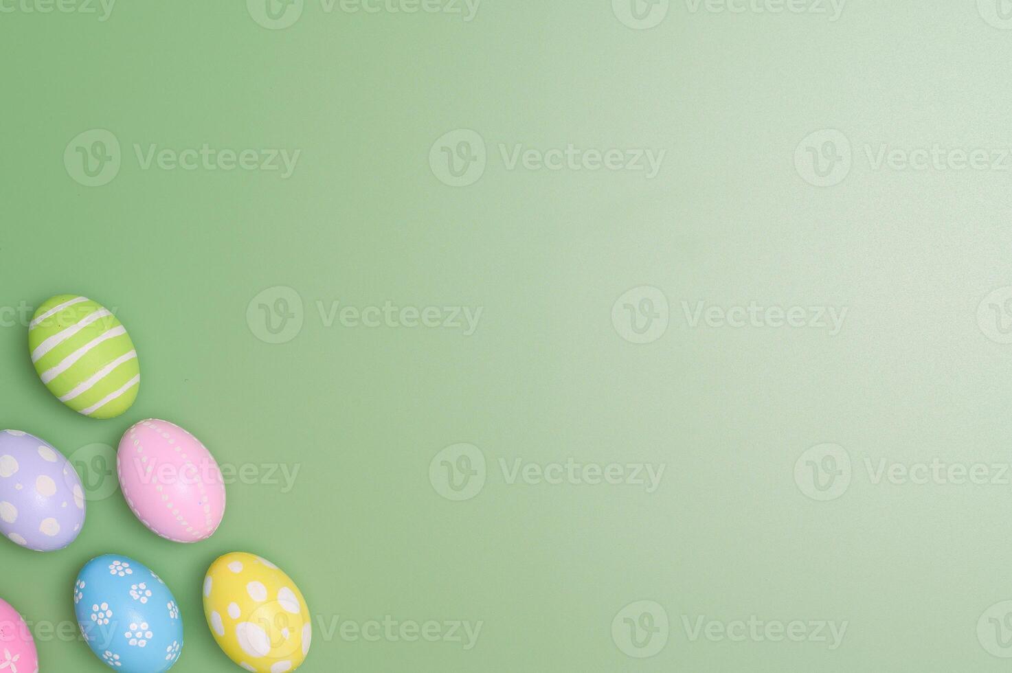 Happy Easter holiday greeting card design concept. Colorful Easter Eggs and spring flowers on pastel green background. Flat lay, top view, copy space. photo