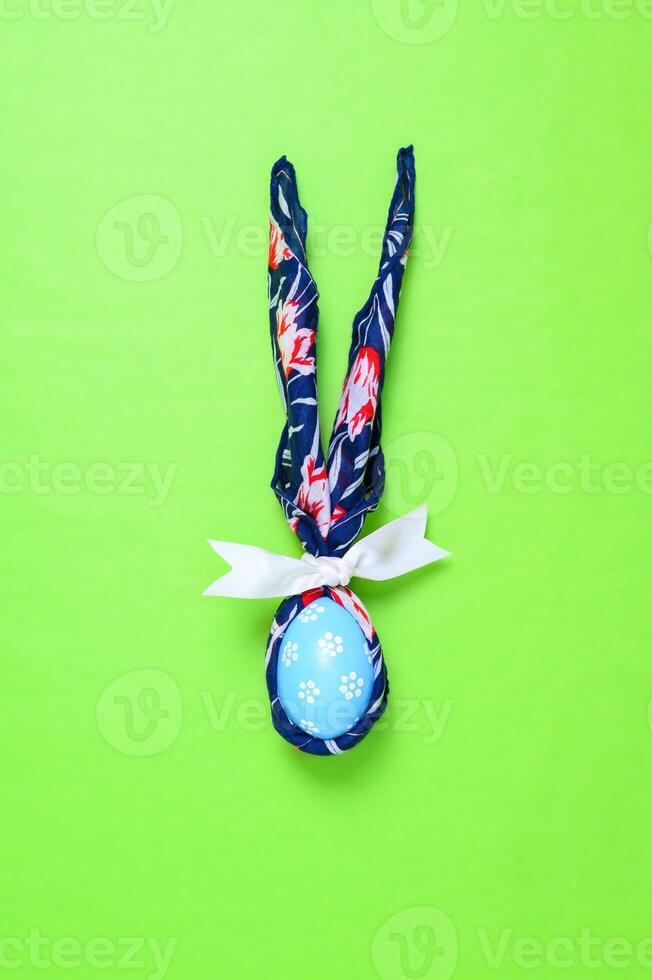 Happy Easter holiday greeting card design concept. Colorful Easter Eggs and spring flowers on pastel green background. Flat lay, top view, copy space. photo