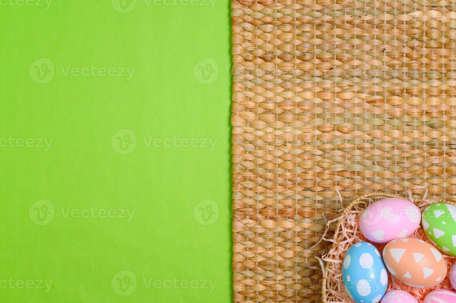 Happy Easter holiday greeting card design concept. Colorful Easter Eggs and spring flowers on pastel green background. Flat lay, top view, copy space. photo