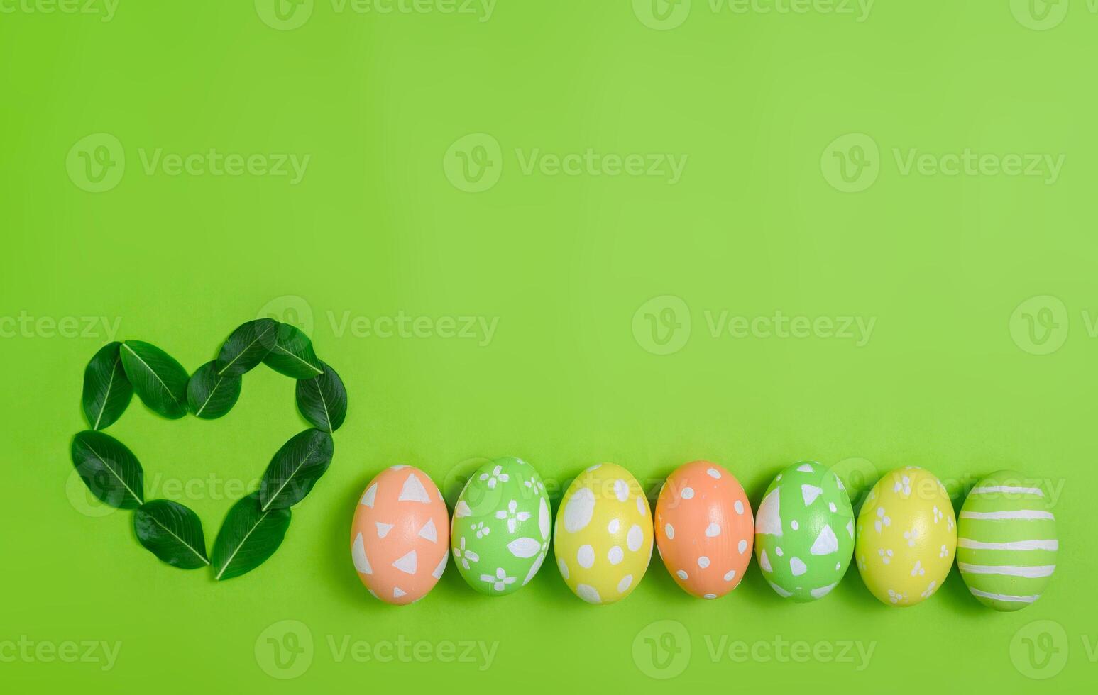 Happy Easter holiday greeting card design concept. Colorful Easter Eggs and spring flowers on pastel green background. Flat lay, top view, copy space. photo