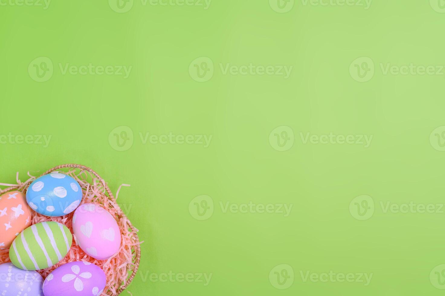 Happy Easter holiday greeting card design concept. Colorful Easter Eggs and spring flowers on pastel green background. Flat lay, top view, copy space. photo