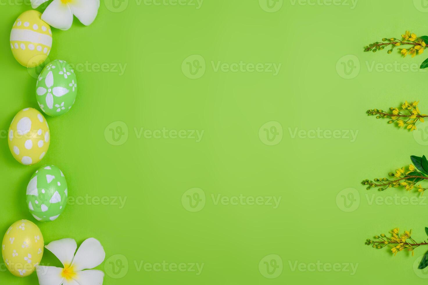 Happy Easter holiday greeting card design concept. Colorful Easter Eggs and spring flowers on pastel green background. Flat lay, top view, copy space. photo