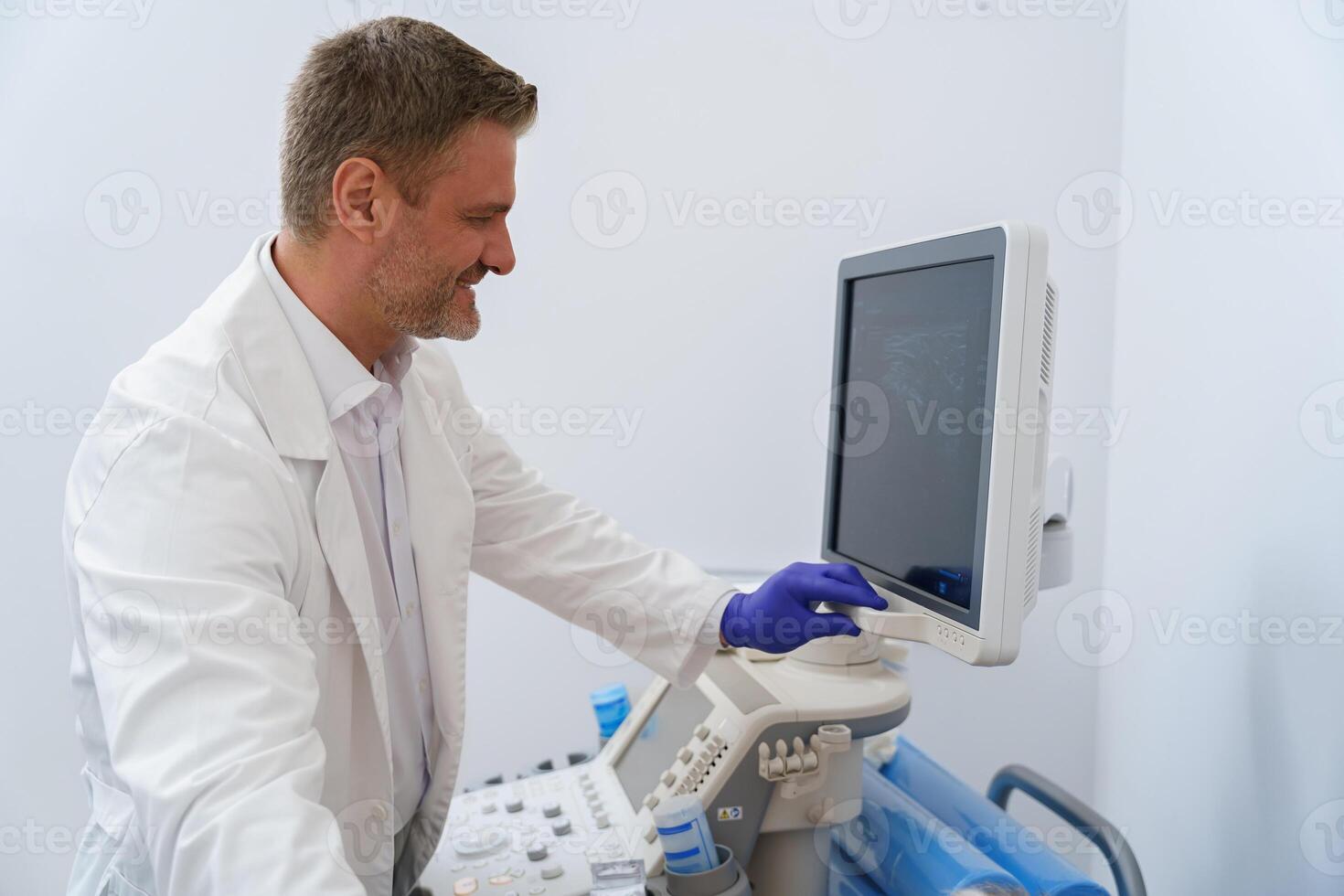 Confident smiling sonographer looking at the screen during the procedure of ultrasound photo
