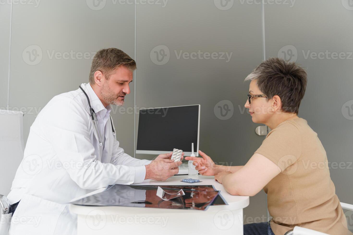 Doctor therapist prescribing pills to female patient during appointment in his office photo