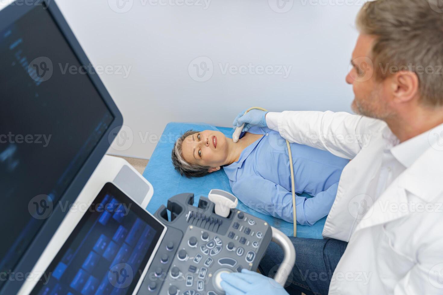 Middle aged woman patient during ultrasound examination of thyroid lying on couch in medical office photo