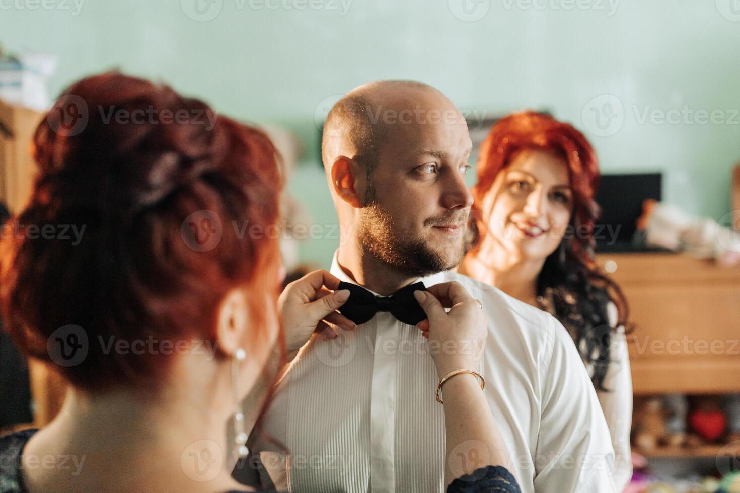 A man is getting ready to wear a black bow tie photo