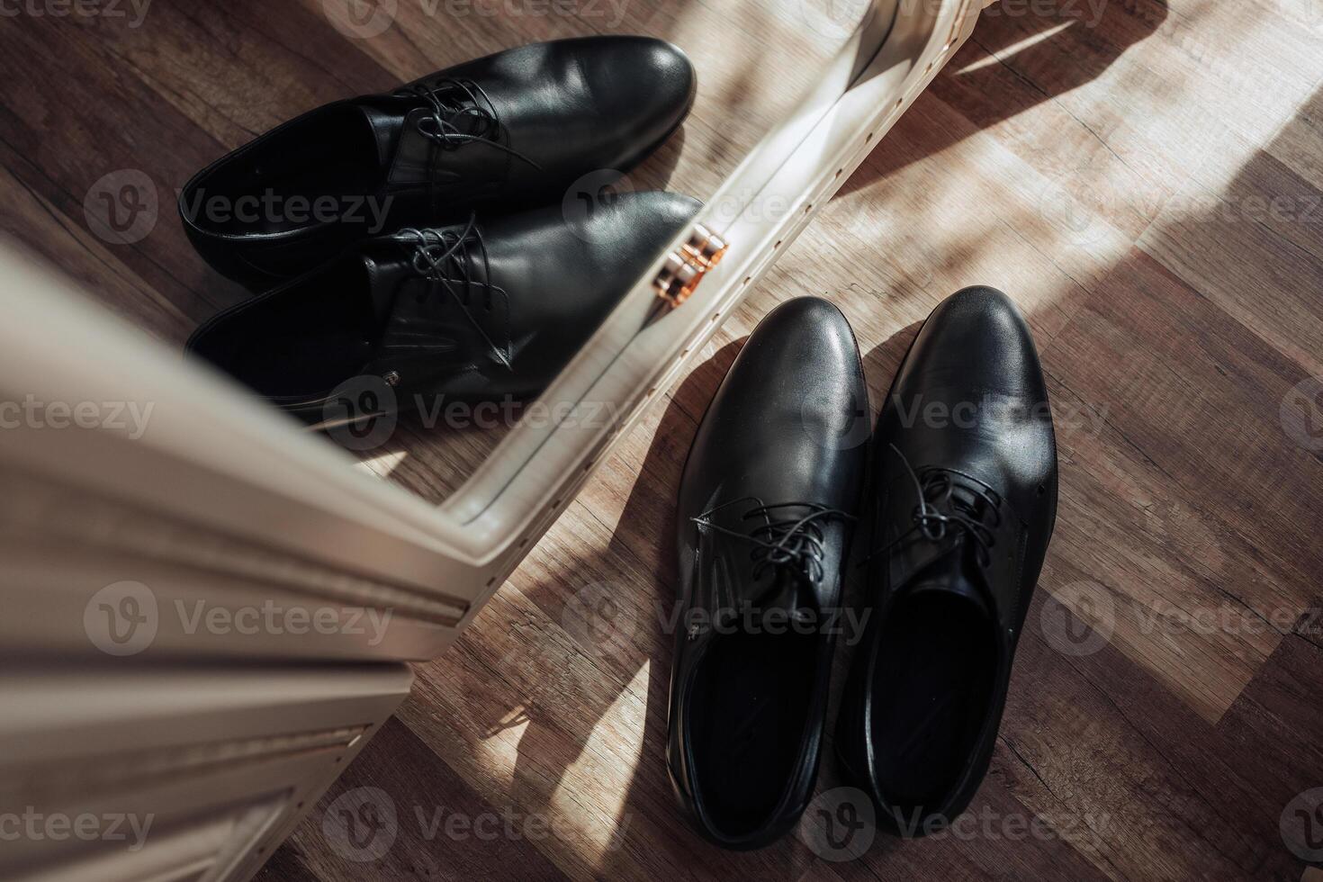 Two black shoes are reflected in a mirror photo