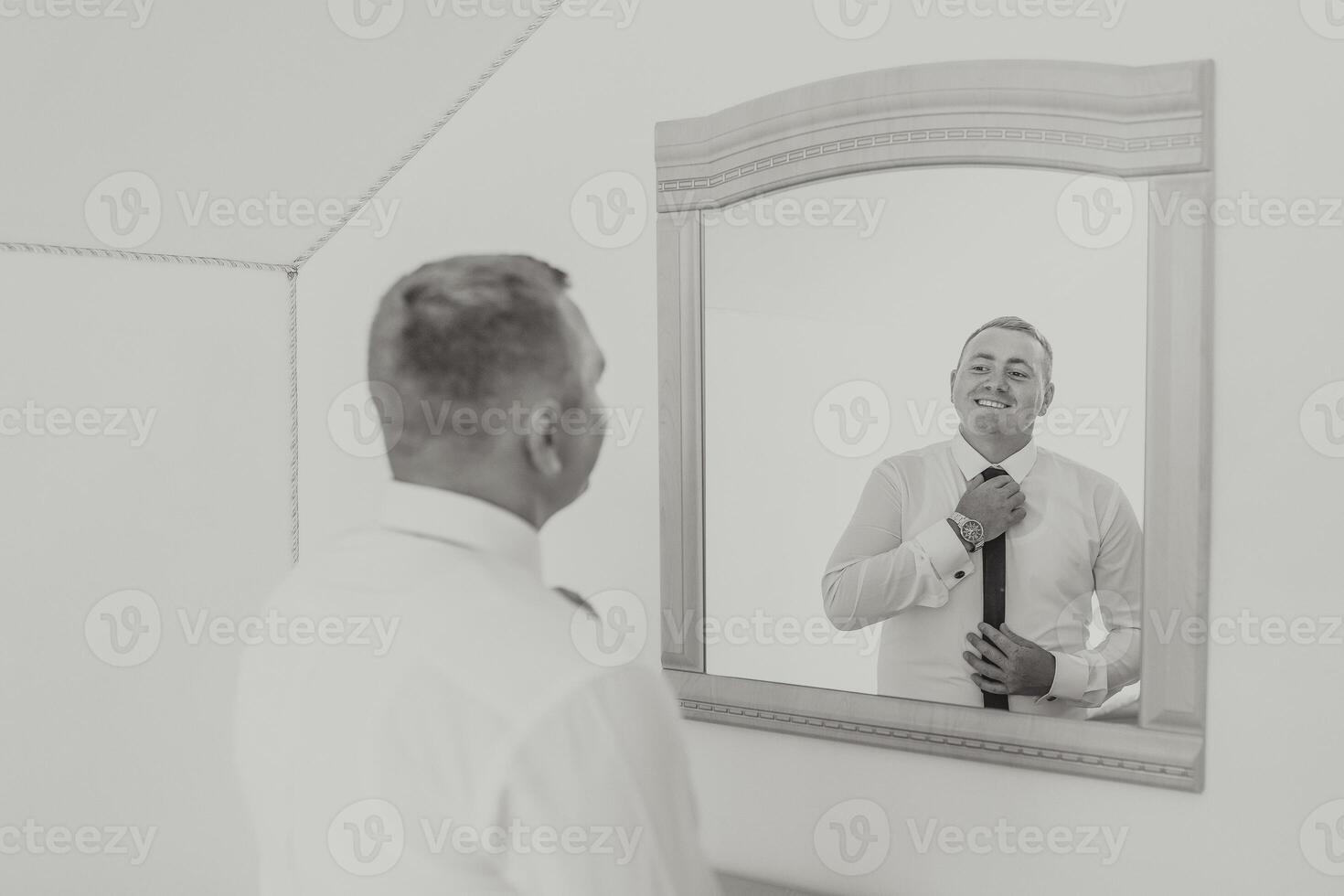 A man is getting ready to tie his tie in front of a mirror photo