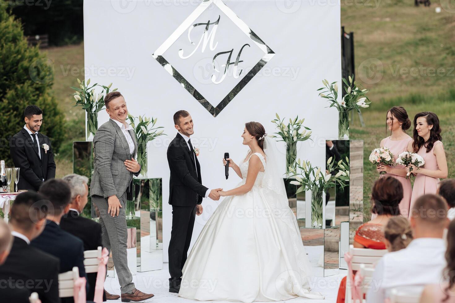 A bride and groom are getting married in front of a large crowd photo