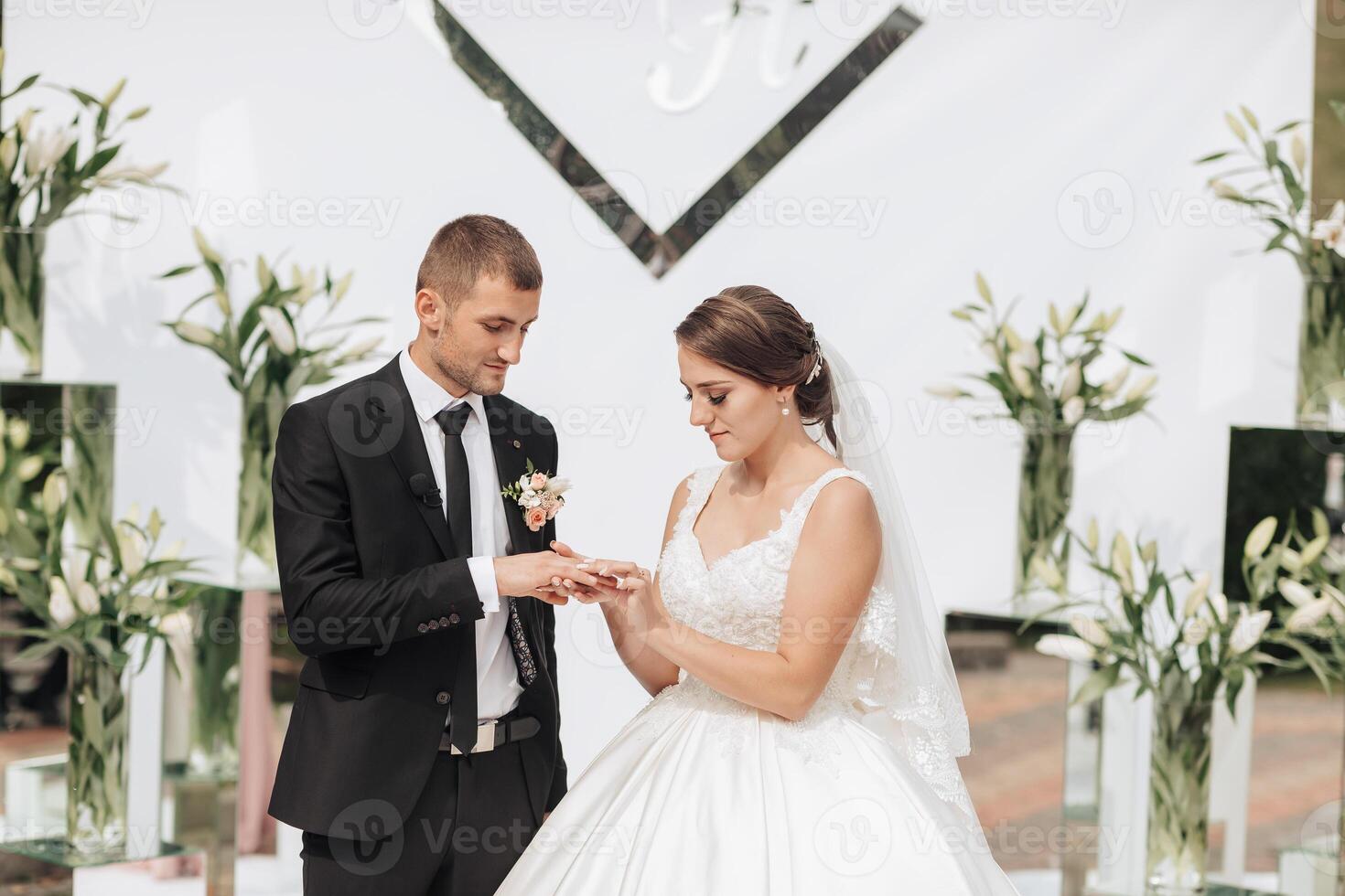 A bride and groom are getting married in front of a large mirror photo