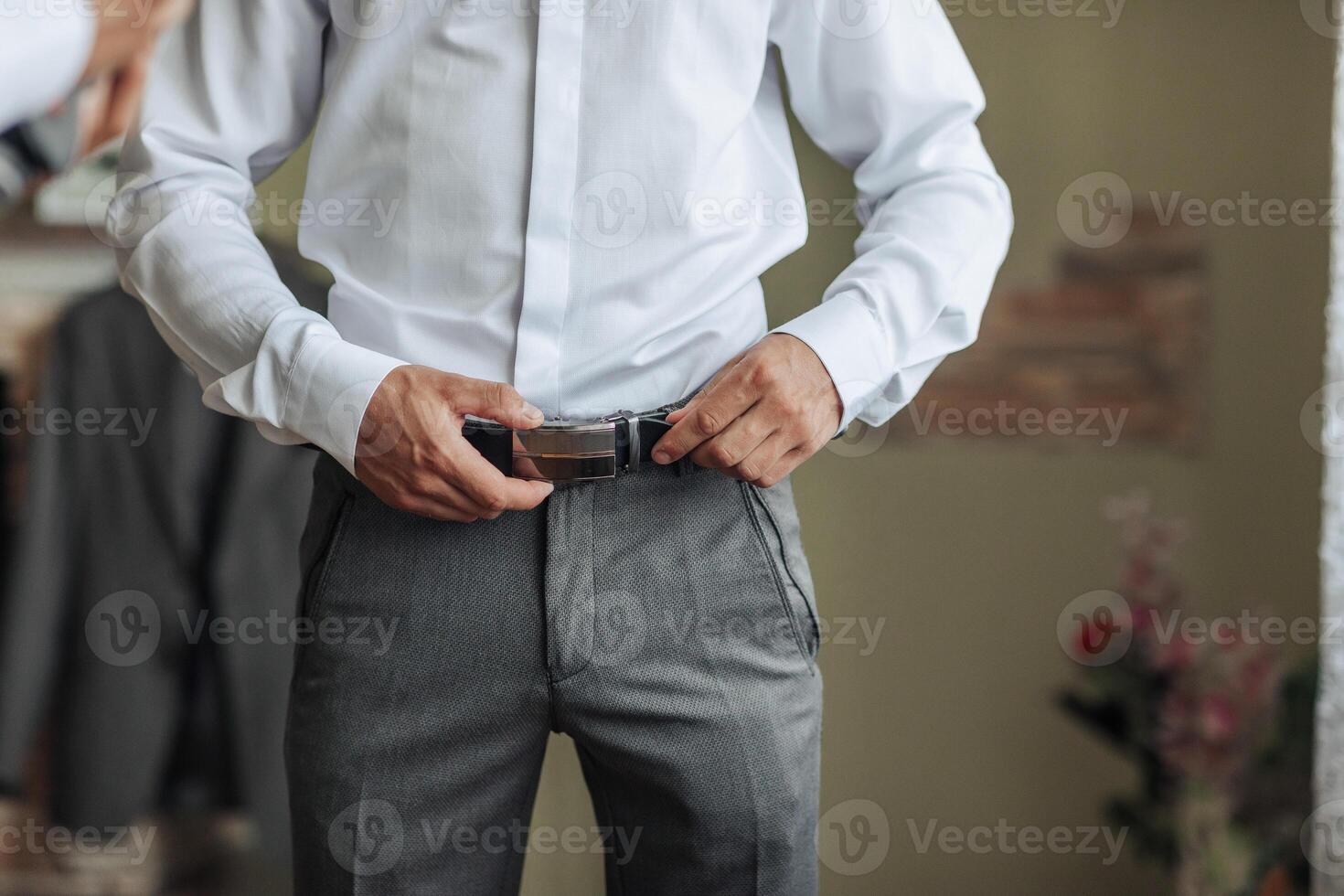 A man is adjusting his belt while standing in front of a mirror photo