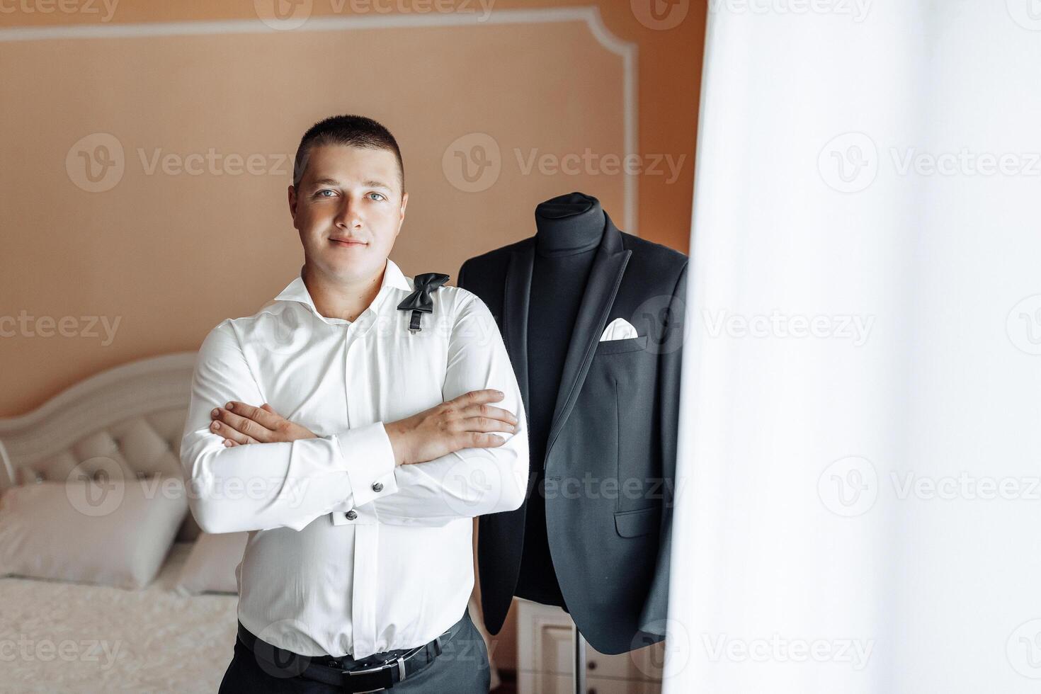 A man in a suit stands in front of a mannequin wearing a black suit photo